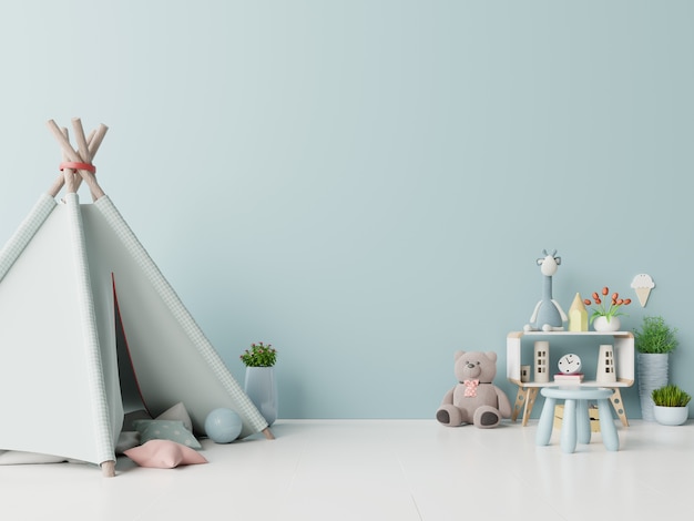 Children playroom with tent and table sitting doll on empty blue wall background.
