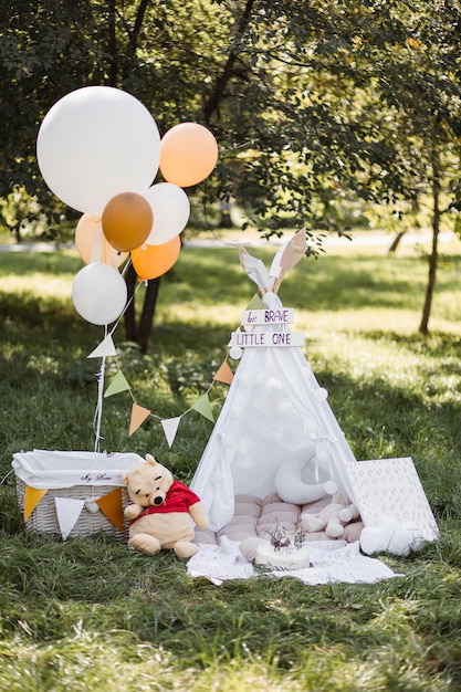 Colorful wigwam with toys balloons and cake on nature