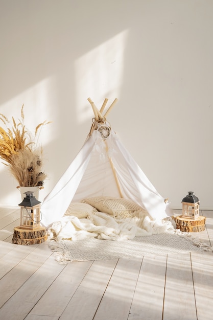 White fabric wigwam and native american decor in a children’s room on a sunny day.