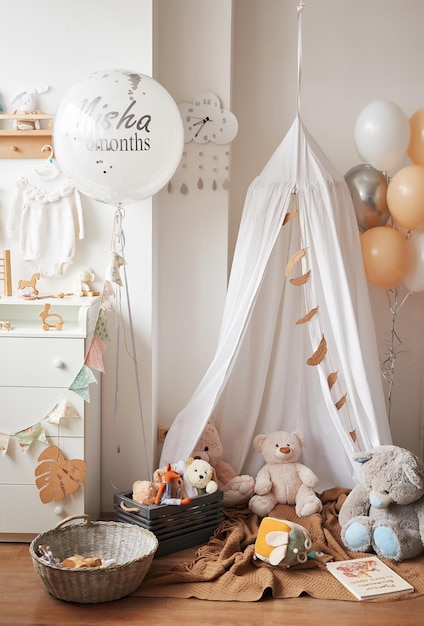 Scandinavian style white interior children’s room, bedroom, nursery. Baby cot with canopy. Wooden shelves and toys. Canopy tent, textile kite and balloons